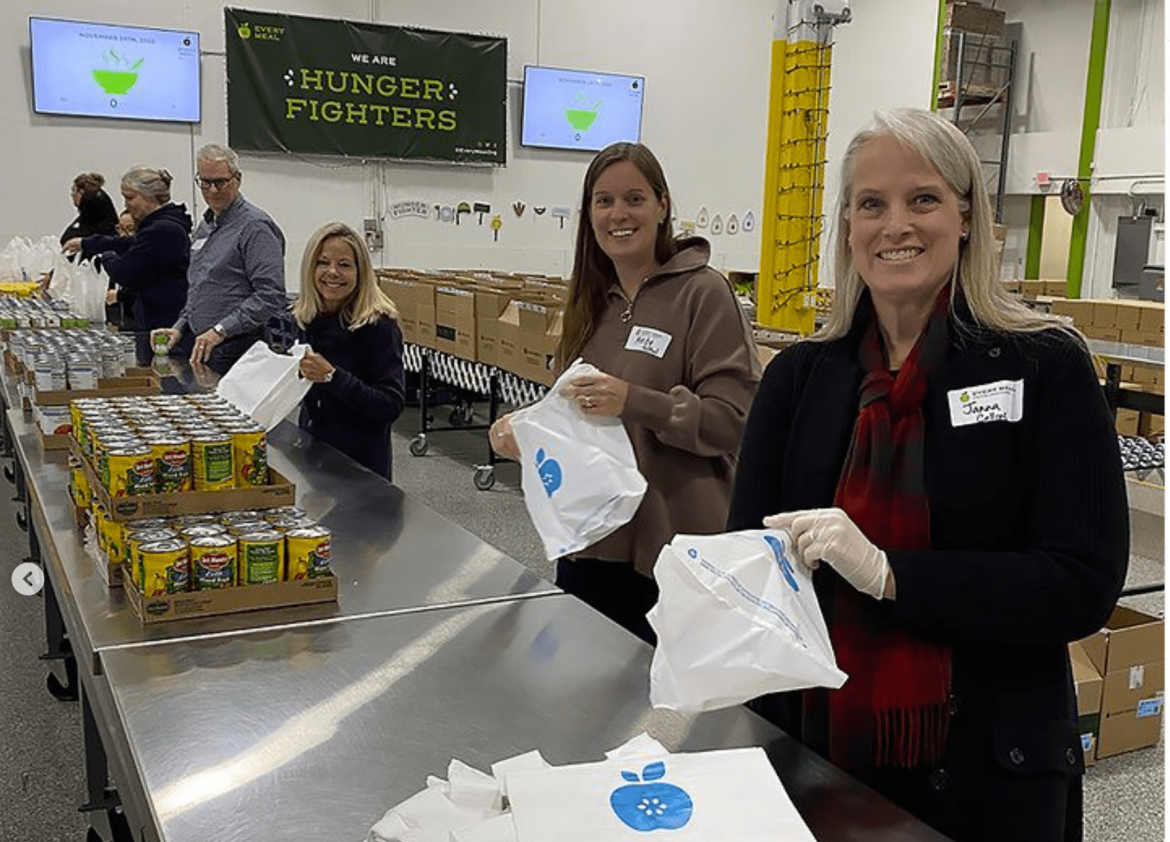 Volunteer Page - Close up of volunteers packing food bags in the Every Meal warehouse