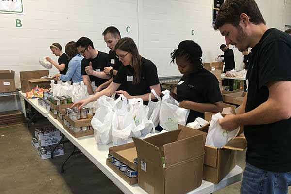 Volunteer Page - Volunteers packing bags in the Every Meal warehouse