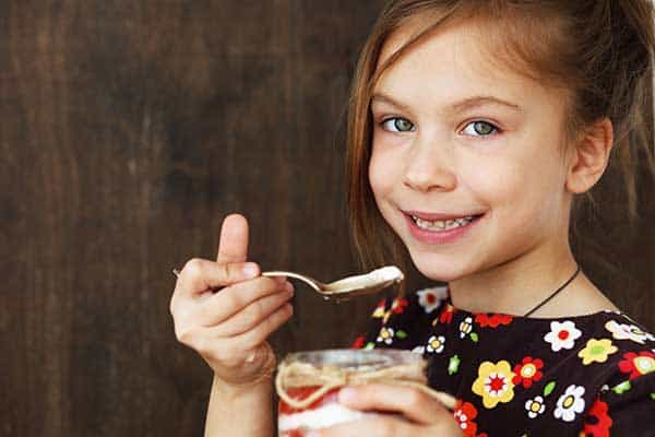 Other Ways To Give - Yung Girl Eating yogurt with a spoon and smiling