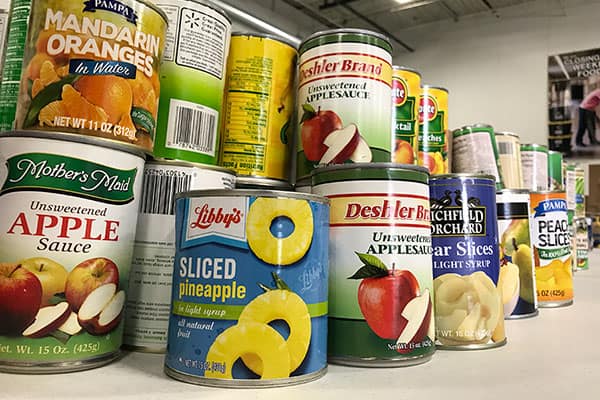 Give Food - Cans of fruit and vegetables on a table in the warehouse